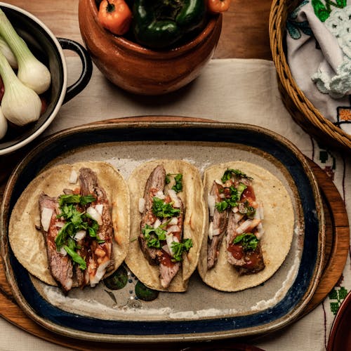 Sliced Beef Steak and Green Vegetable on Top of Tortilla Placed on a Ceramic Plate